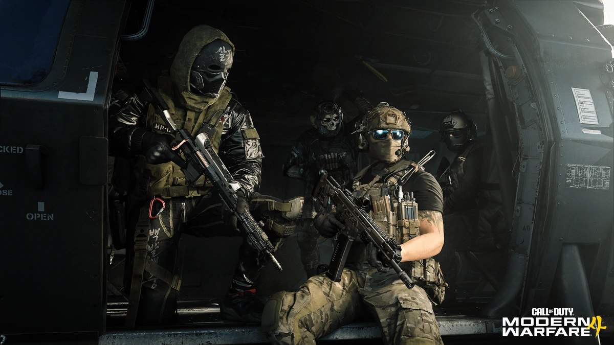 Four armed Modern Warfare 4 operators gather inside the open door of a helicopter.
