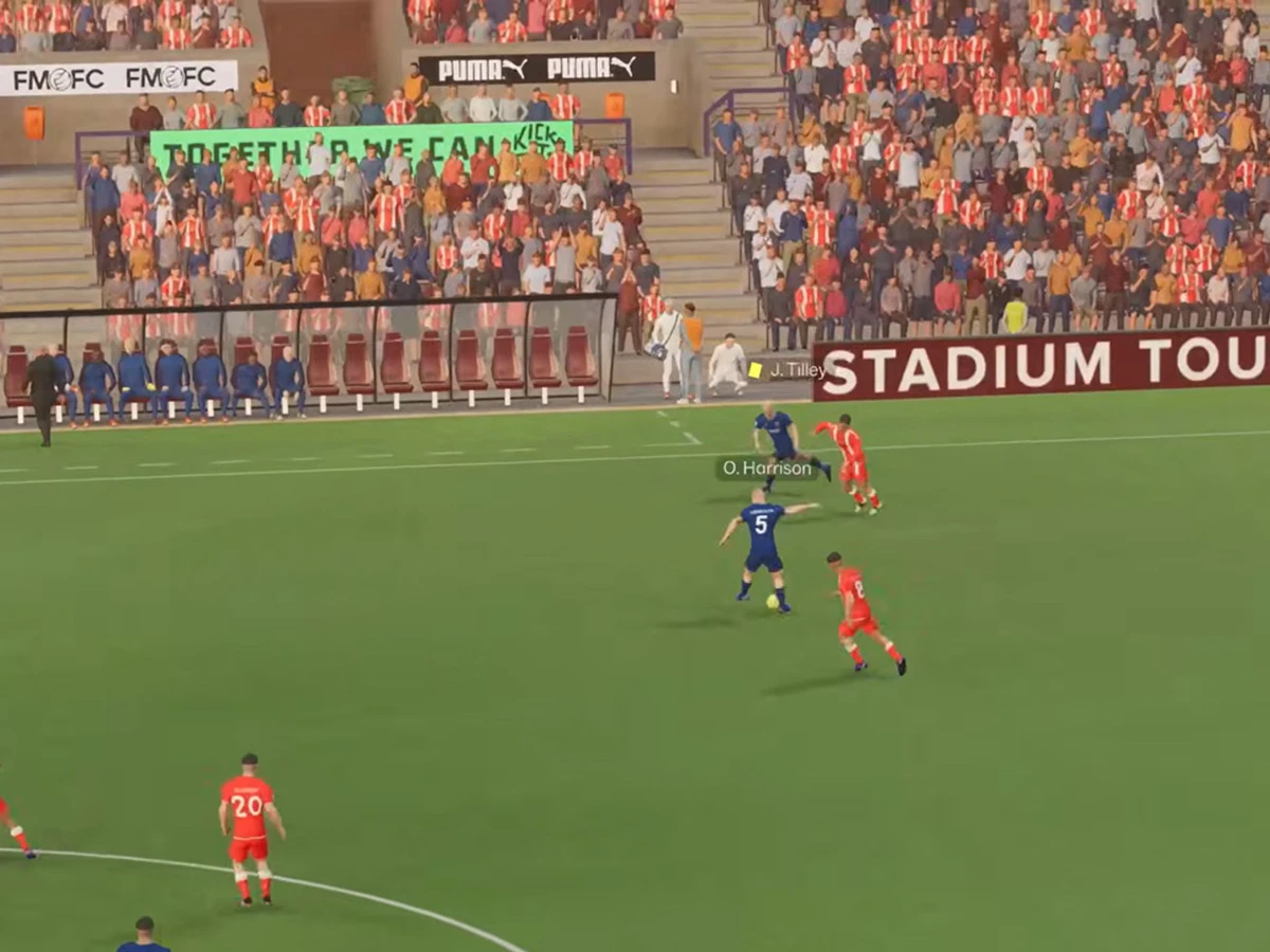 Red-shirted and blue-shirted players contest the ball near the touchline in Football Manager 27
