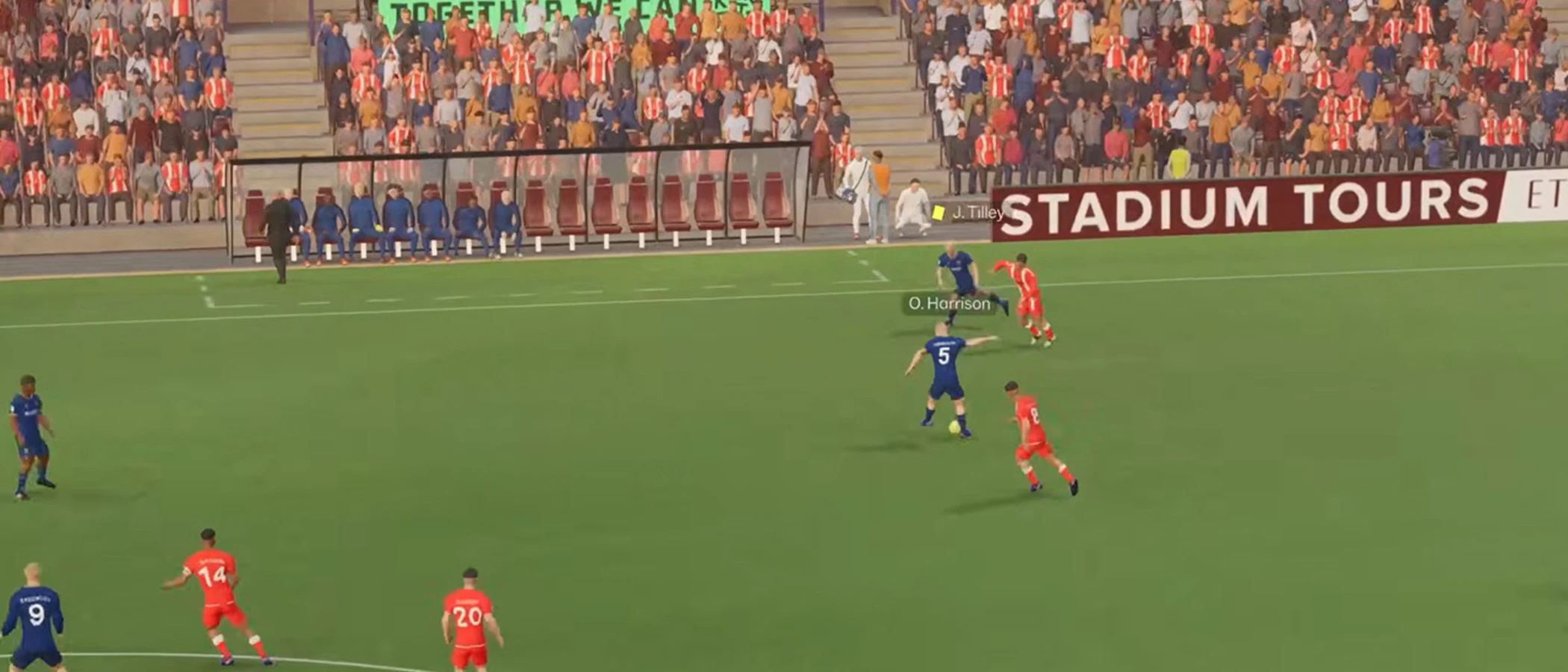 Red-shirted and blue-shirted players contest the ball near the touchline in Football Manager 27
