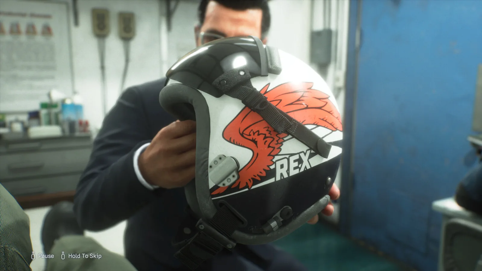 REX holds a white flight helmet with an orange bird design in a briefing room.