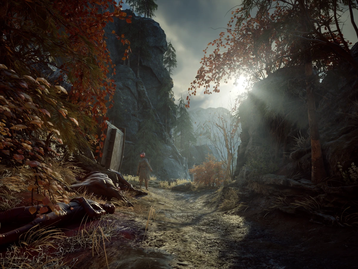 A soldier stands beside a rocky forest path strewn with bodies in Valor Mortis.