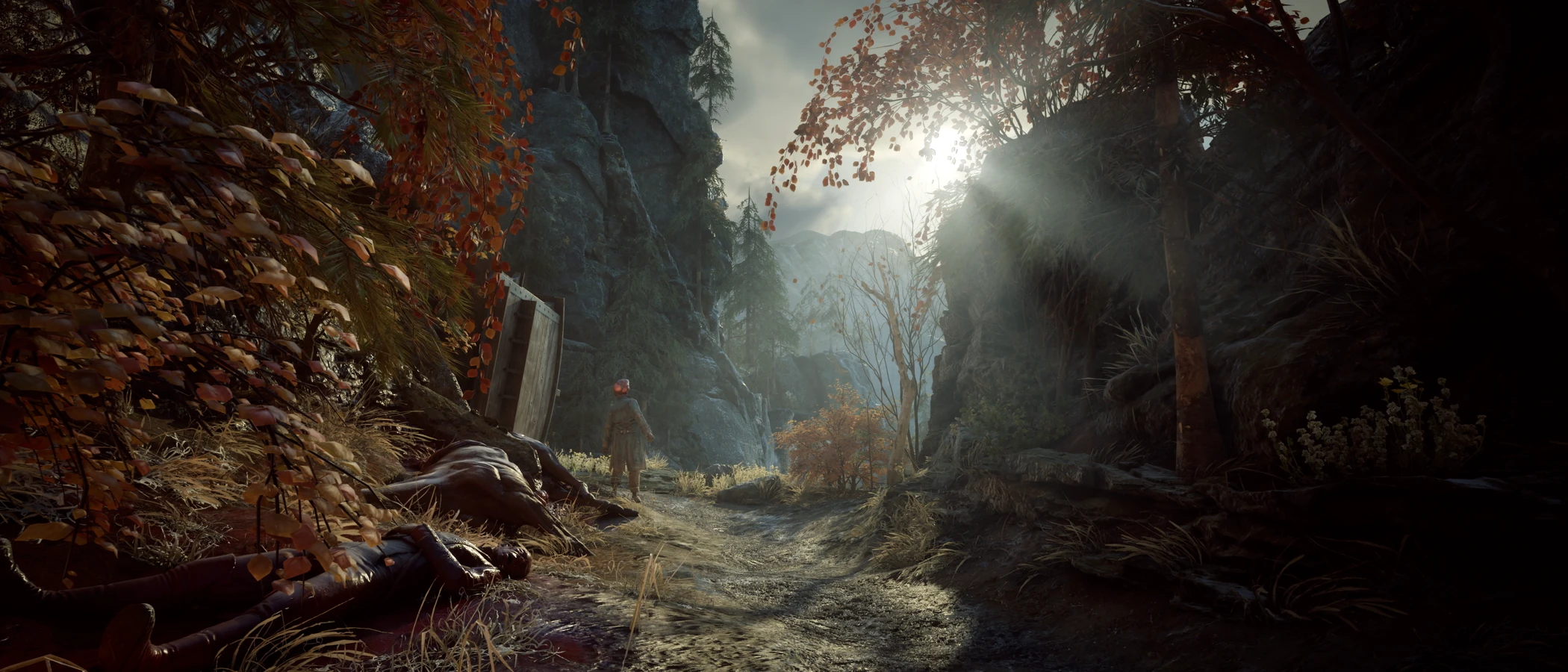 A soldier stands beside a rocky forest path strewn with bodies in Valor Mortis.