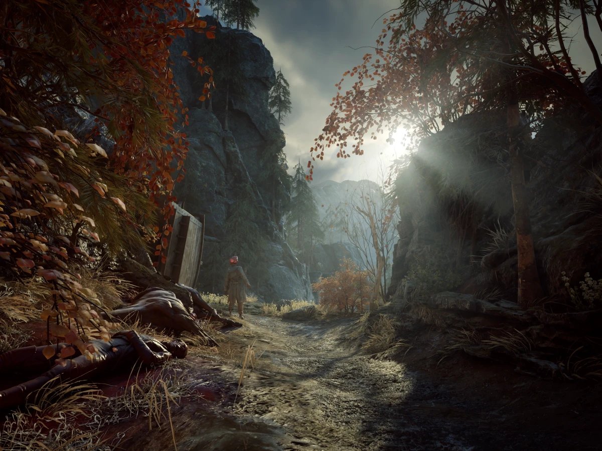 A soldier stands beside a rocky forest path strewn with bodies in Valor Mortis.