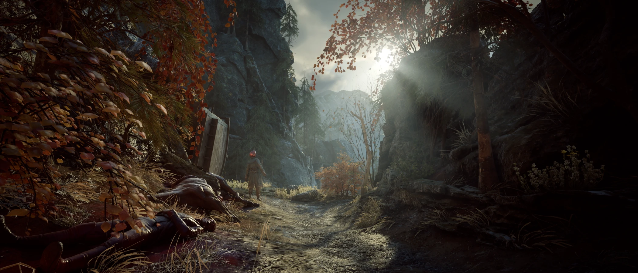 A soldier stands beside a rocky forest path strewn with bodies in Valor Mortis.