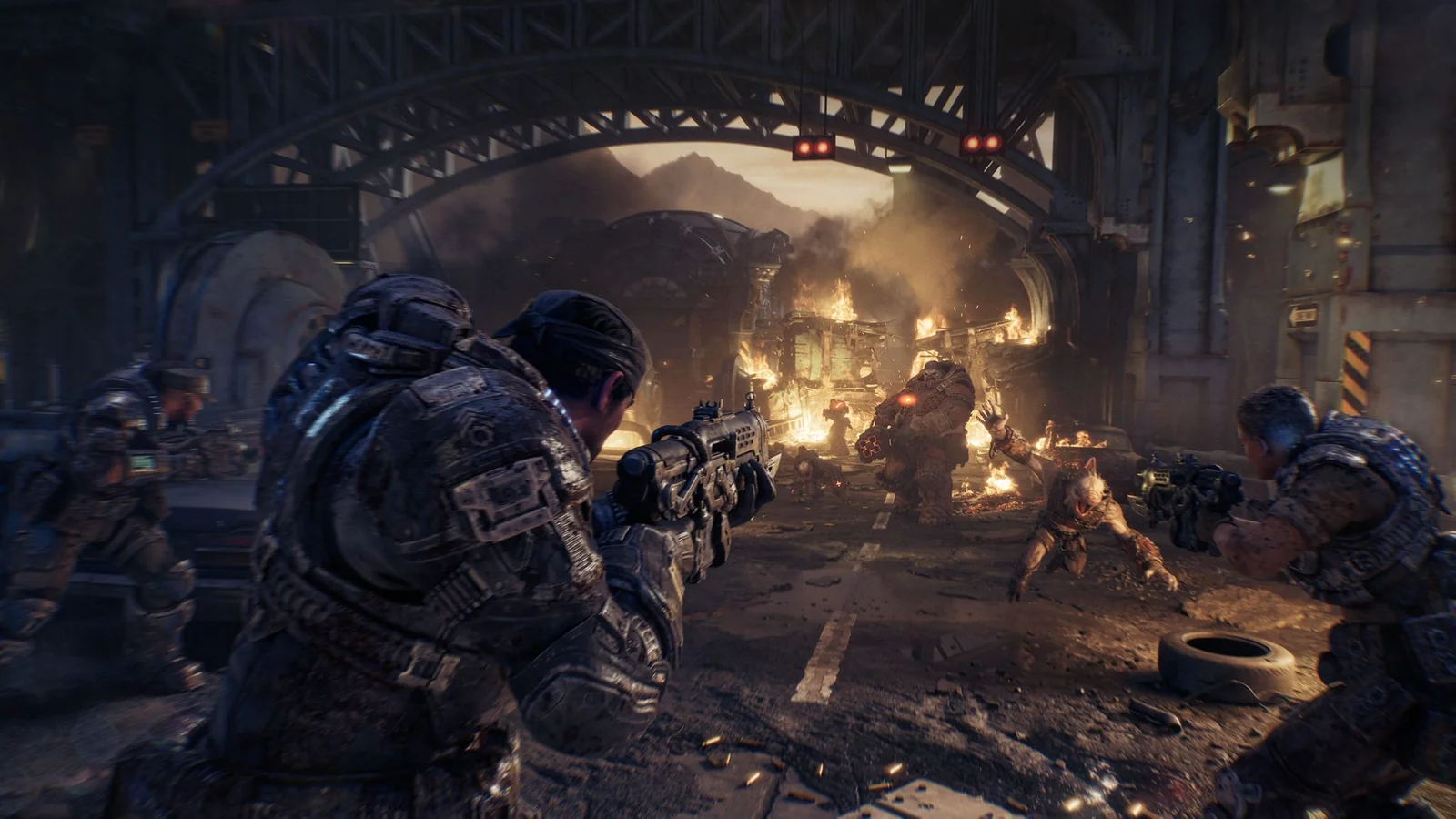 Marcus Fenix and his squad fire at Locust enemies in a burning industrial street.