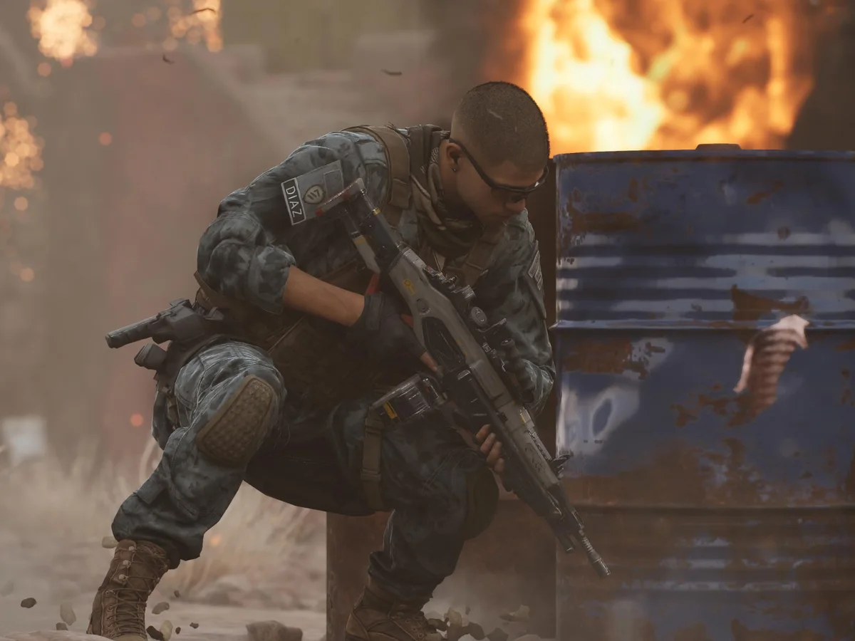 MindsEye protagonist Jacob Diaz crouches beside a barrel amid flames
