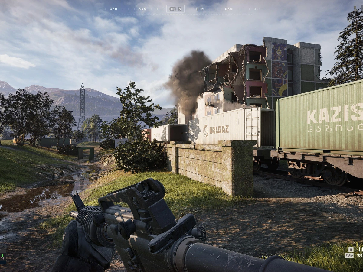 A WARDOGS soldier aims a rifle towards a damaged industrial building beneath a plume of smoke.