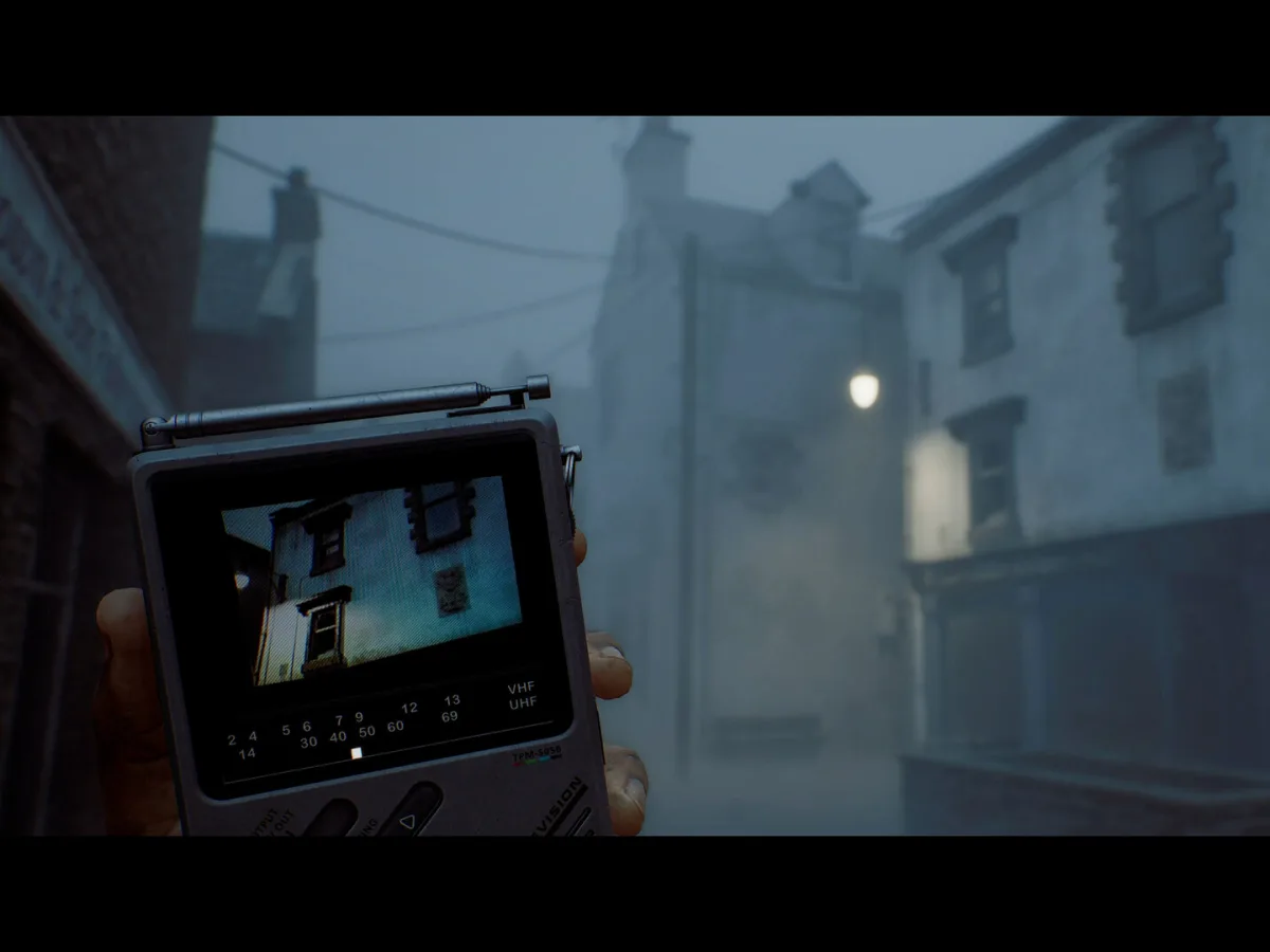 A CRTV pocket television is held up on a foggy street lined with old buildings in Silent Hill: Townfall.