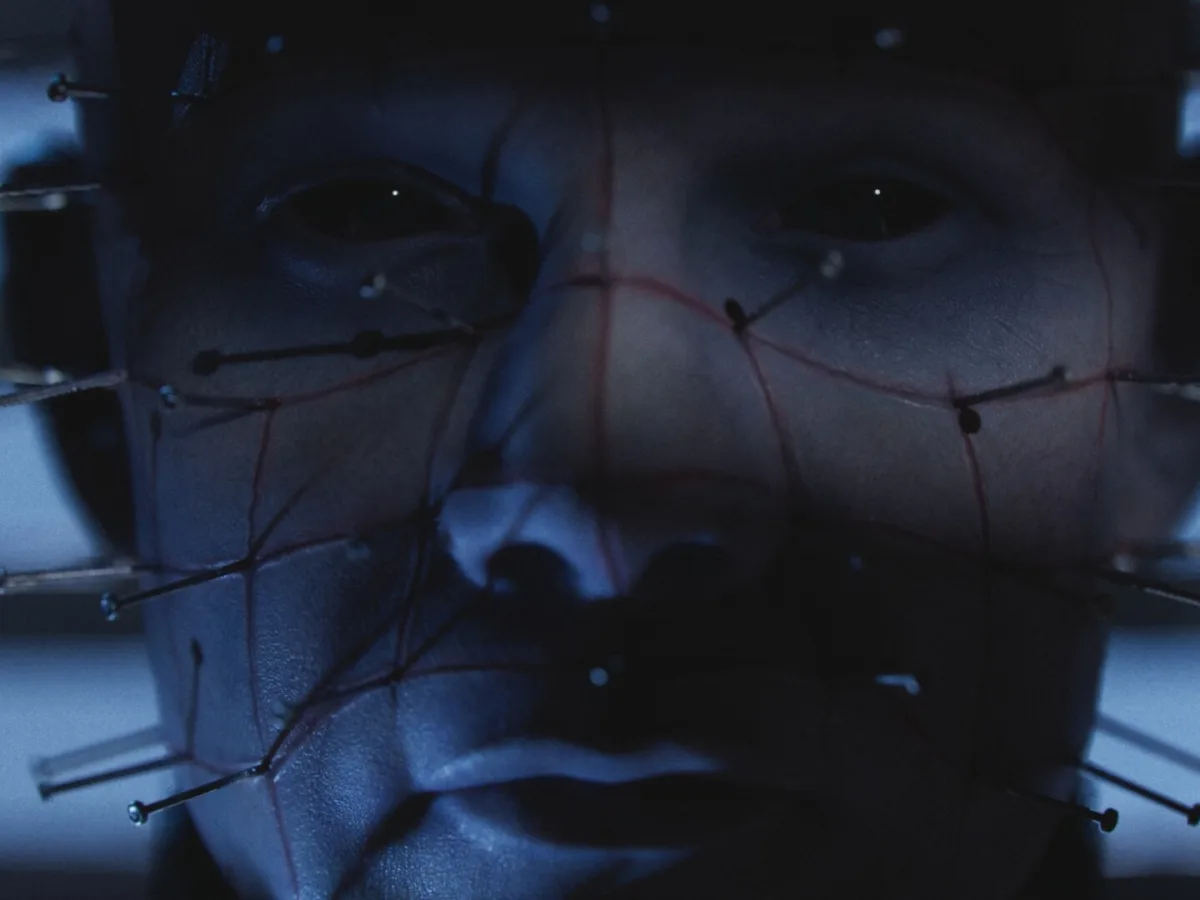 A close-up official game image of Pinhead, his face framed by pins and dark blue light.