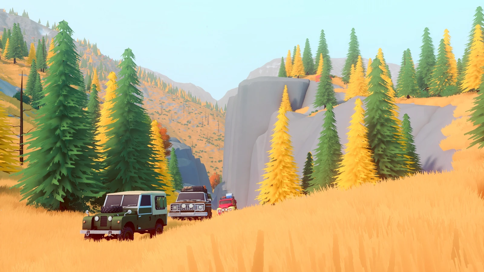 Three off-road vehicles travel through golden grass below a wooded rocky hillside