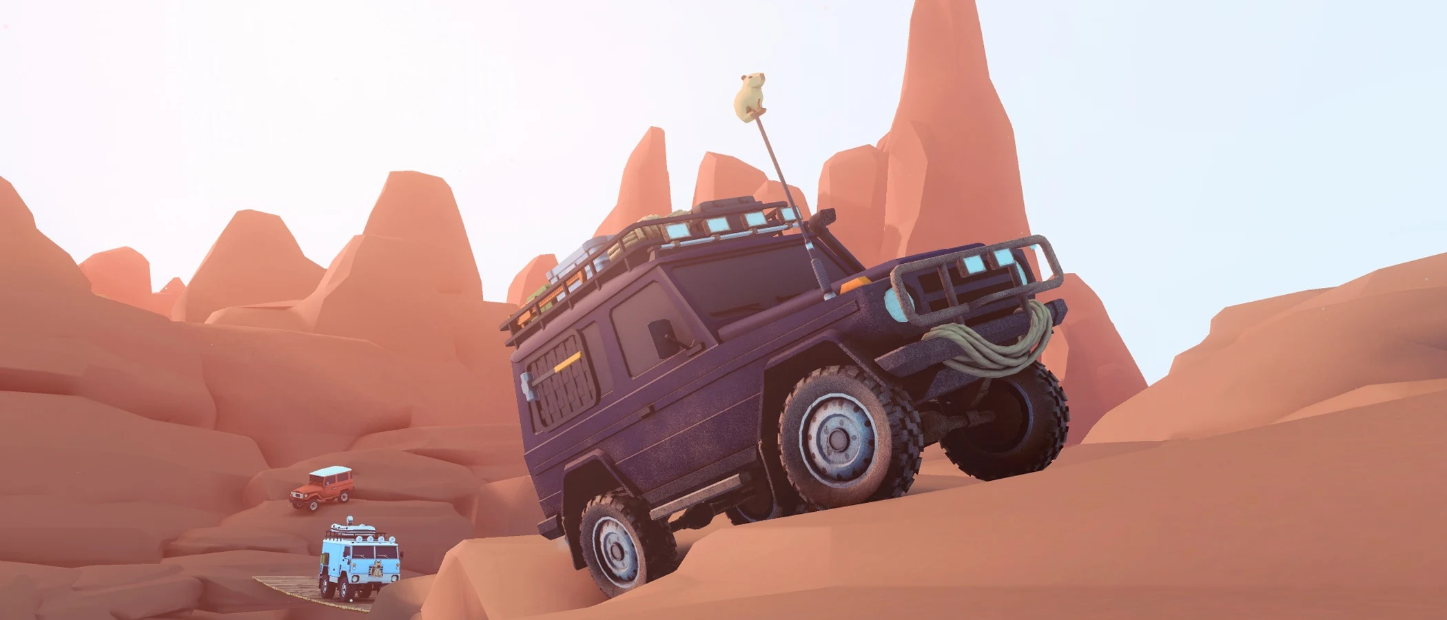A luggage-laden off-road vehicle climbs a sandstone slope above a second car