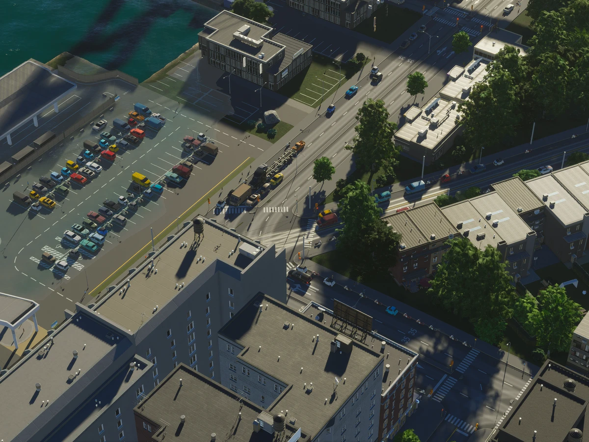 An official Cities Skylines II screenshot of streets and buildings beside a waterfront