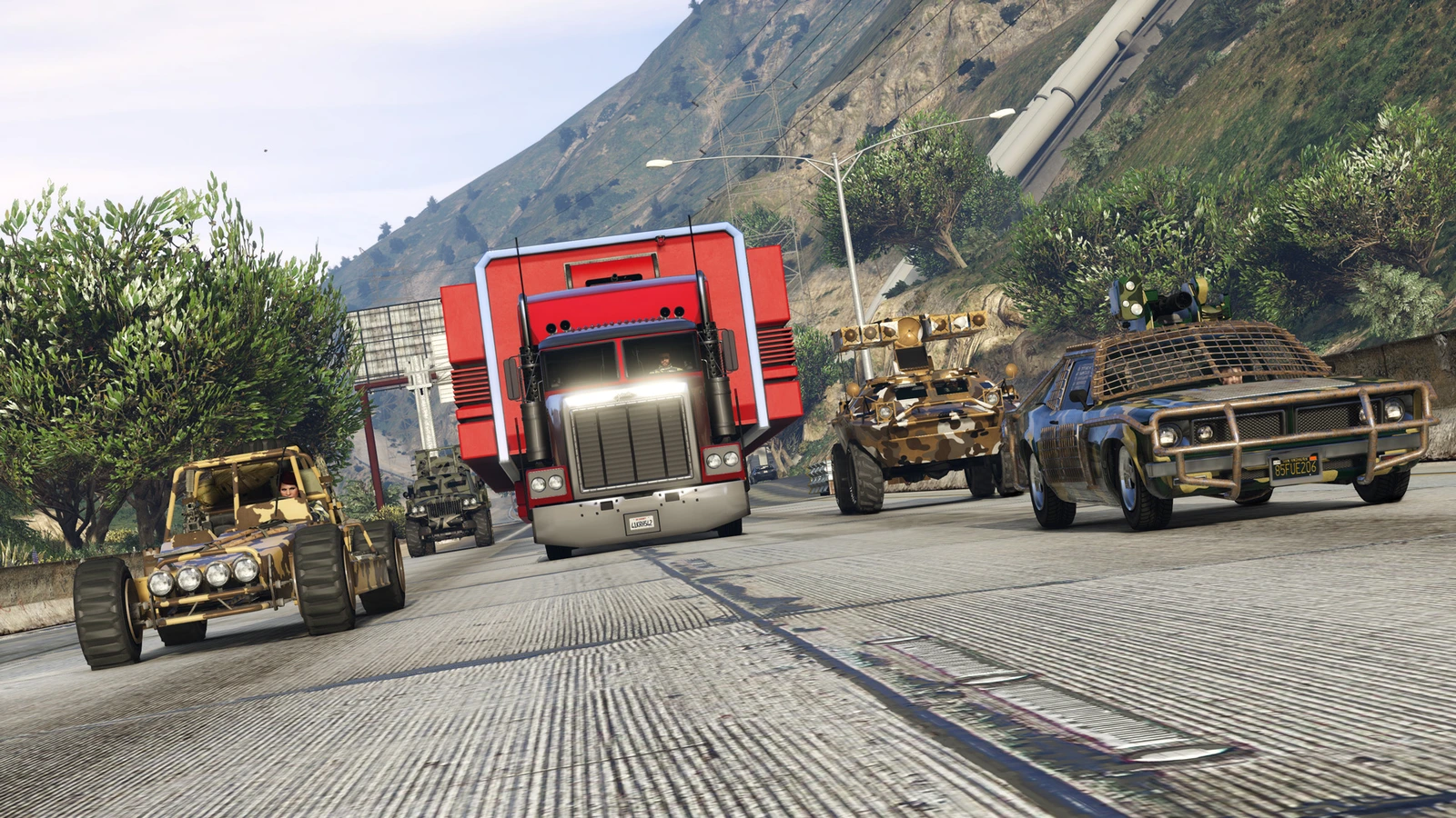 A red Mobile Operations Center truck drives between two armed vehicles.