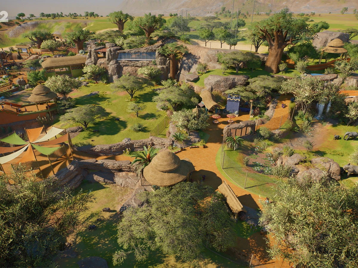 A wide view of themed habitats and paths in a Planet Zoo 2 zoo.