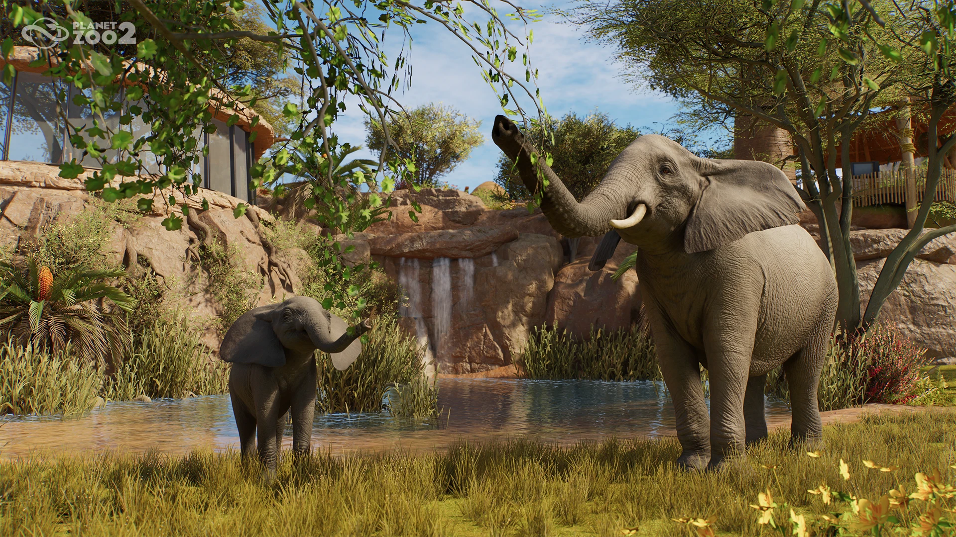 Adult and young elephants stand beside water in a Planet Zoo 2 habitat.