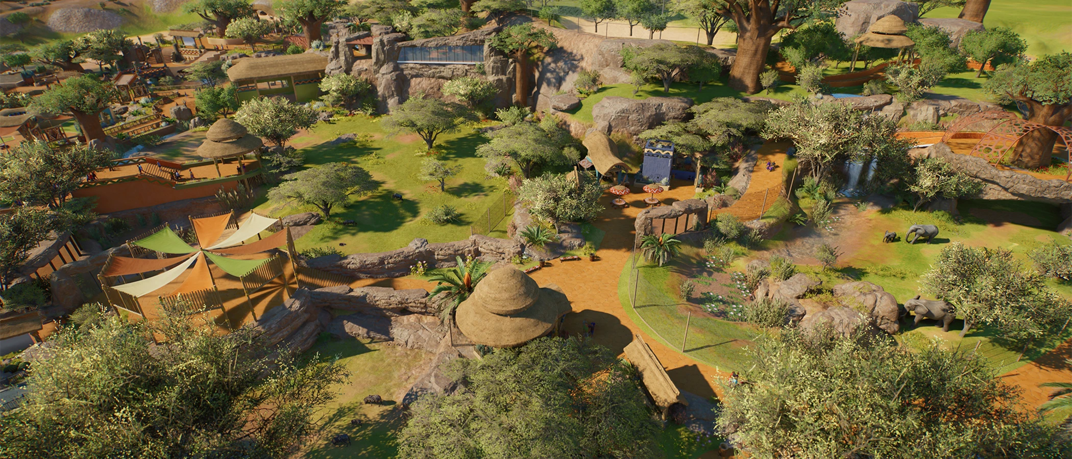 A wide view of themed habitats and paths in a Planet Zoo 2 zoo.