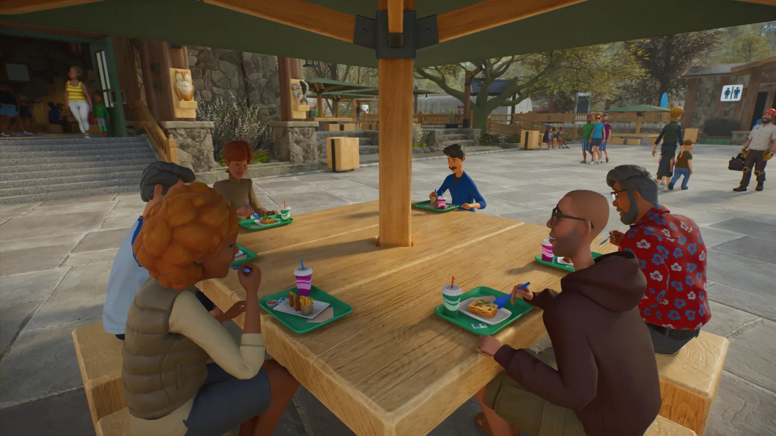 Visitors eat at a shaded table while staff and families move through a Planet Zoo 2 plaza.