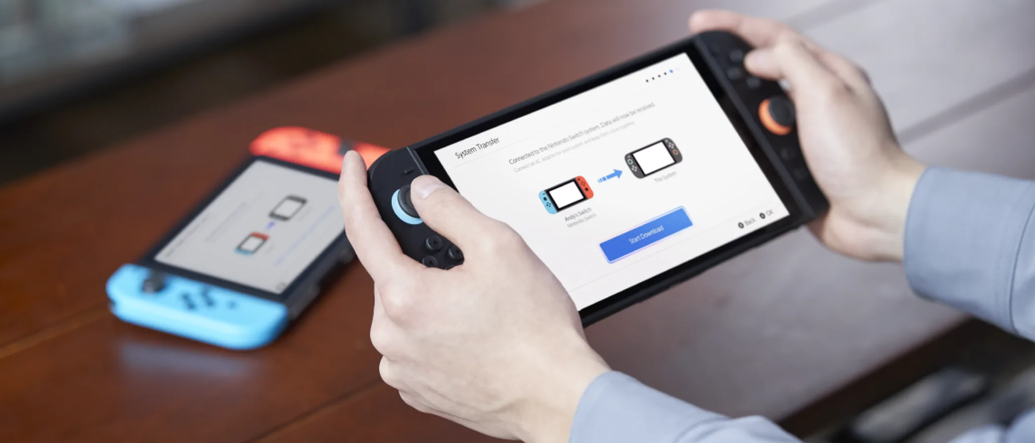Two Nintendo Switch consoles display the system transfer setup screen on a table.