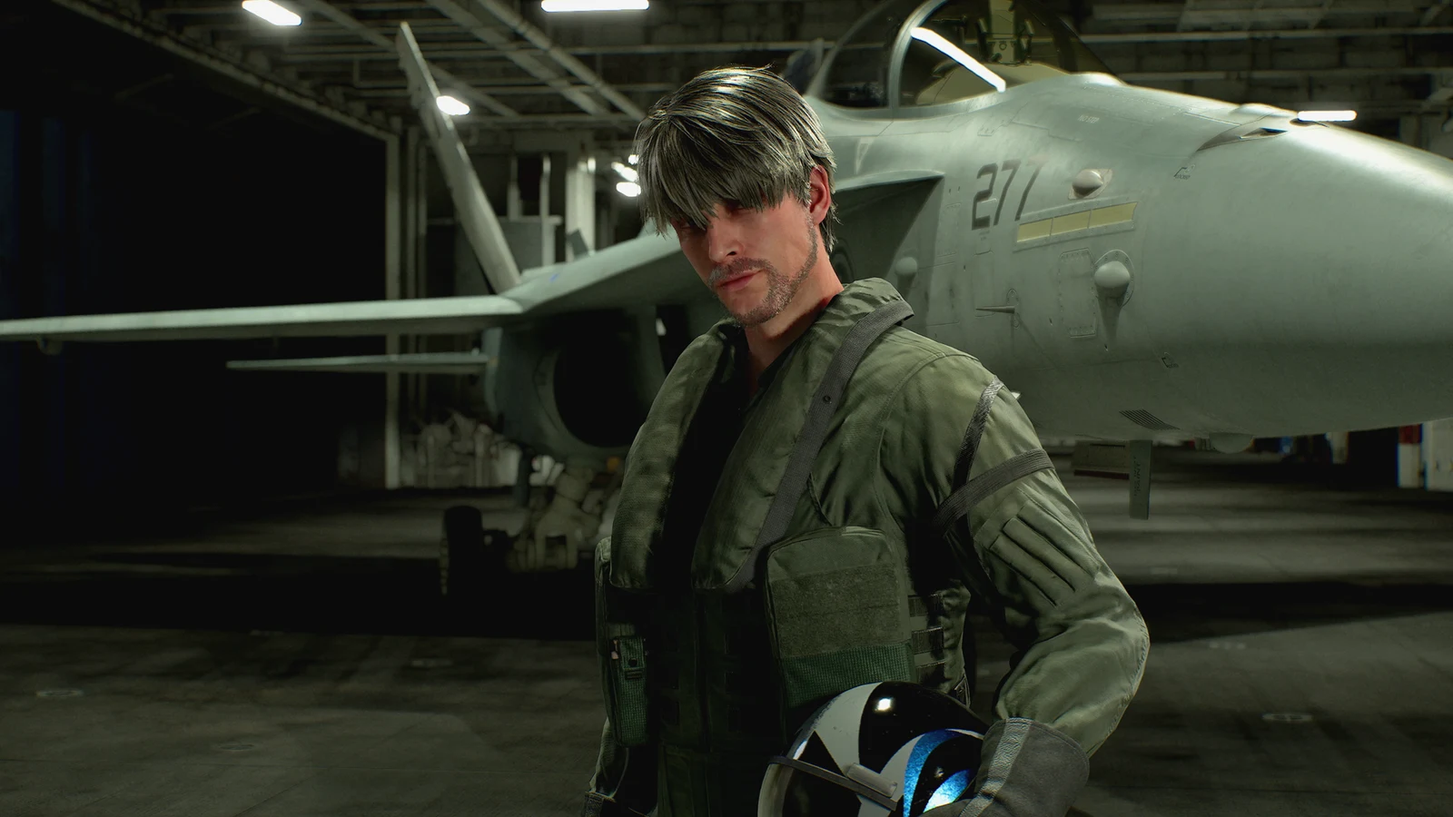 A grey-haired pilot stands beside a fighter jet inside a hangar