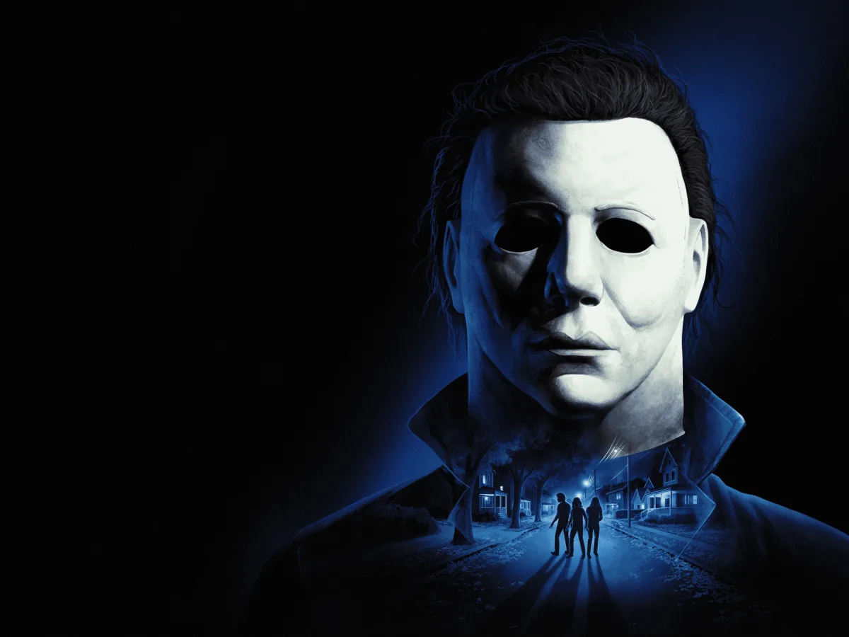 Michael Myers in a white mask is lit in blue above a night-time Haddonfield street.