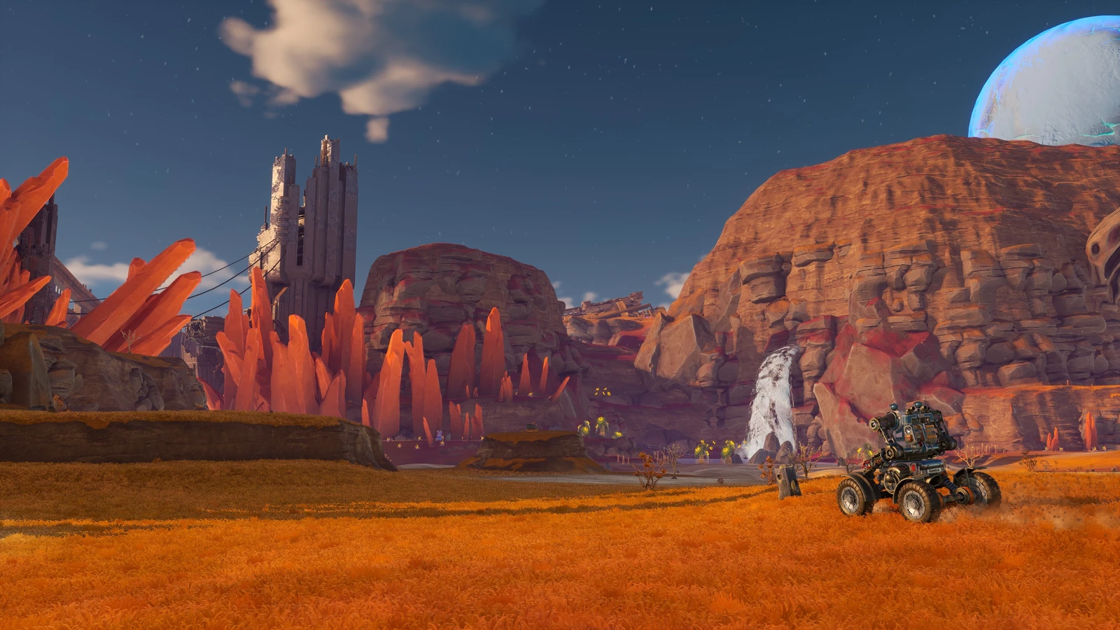 A wheeled mech faces orange crystals, ruined towers and a waterfall in the Sandswept Highlands.