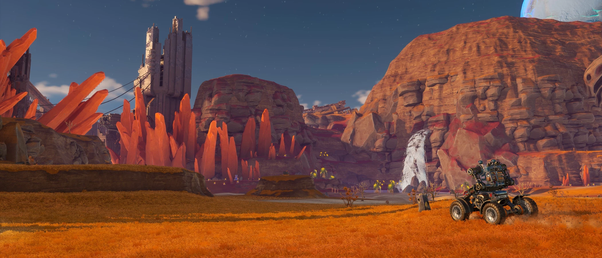 A wheeled mech faces orange crystals, ruined towers and a waterfall in the Sandswept Highlands.