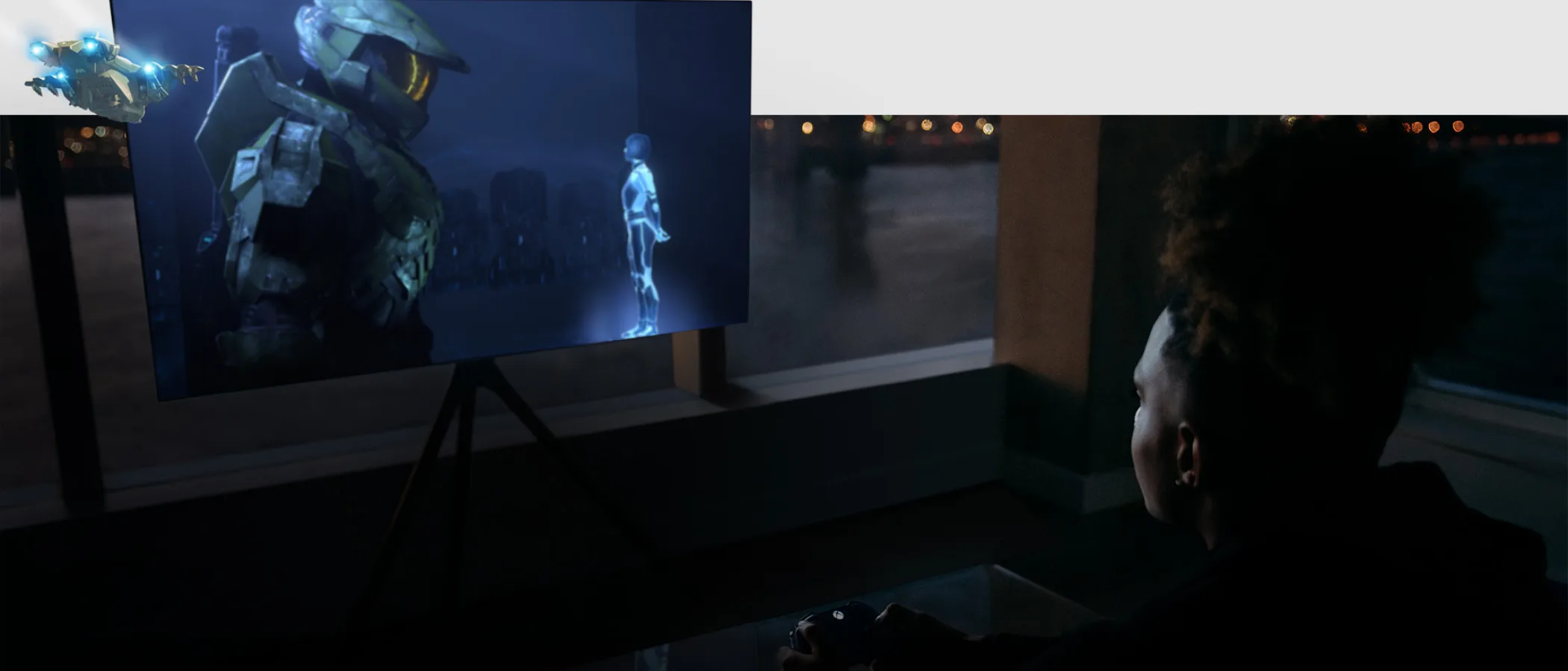 A person with a controller plays an Xbox game on a large television in a living room.